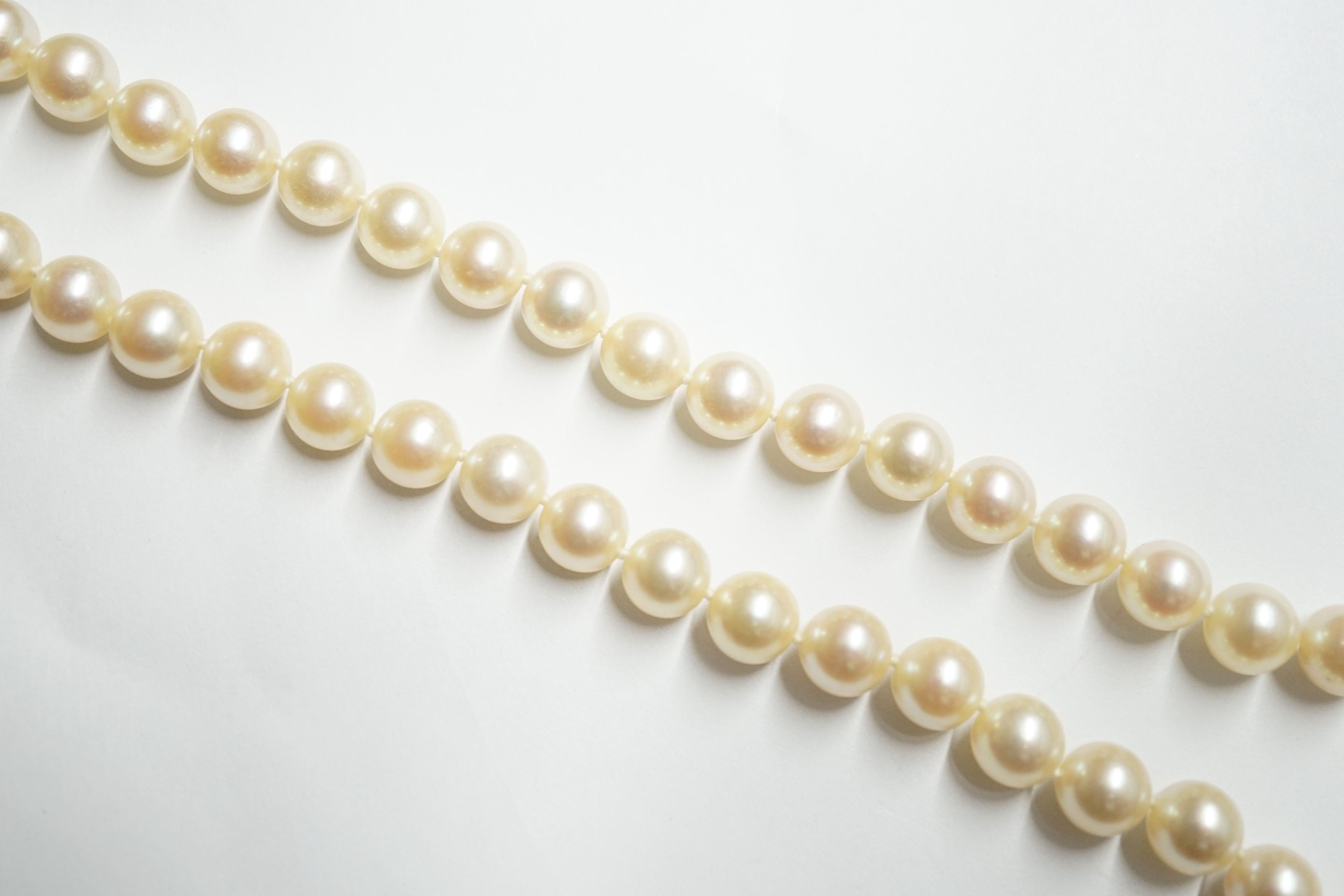 A single strand cultured pearl necklace, with French white metal (18ct mark), sapphire, diamond and cultured pearl set clasp, bearing the signature 'Cartier', 60cm. Condition - fair